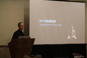 Image of a man giving a presentation, with an image of the joker dressed as ronald macdonald