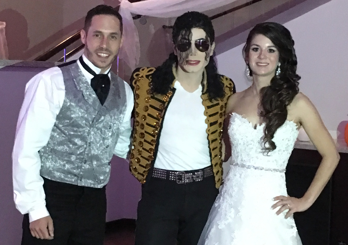 Image of my wife and I in our wedding attire, with a michael jackson impersonator between us