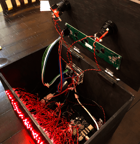 Trashbox with a lifted up lid, looking inside. Red wires connect all the components